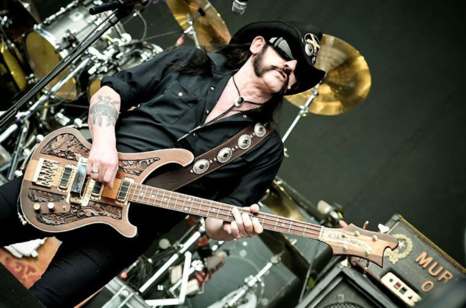 Lemmy steht mit Bass und Sonnenbrille auf der Bühne vor Marshall-AMPs