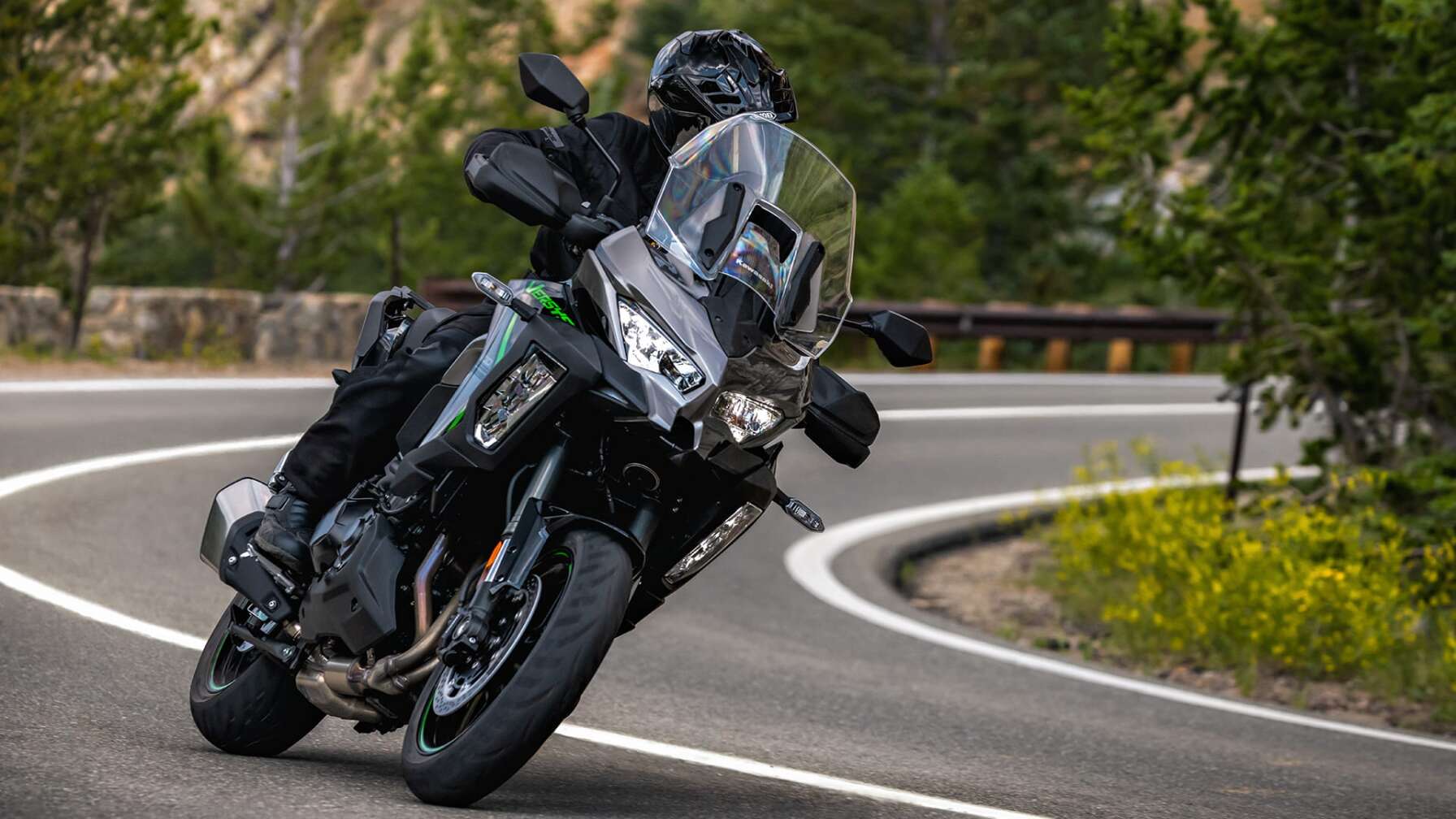 Eine Kawasaki Versys 1100 SE fährt auf einer Straße, im Hintergrund Wald