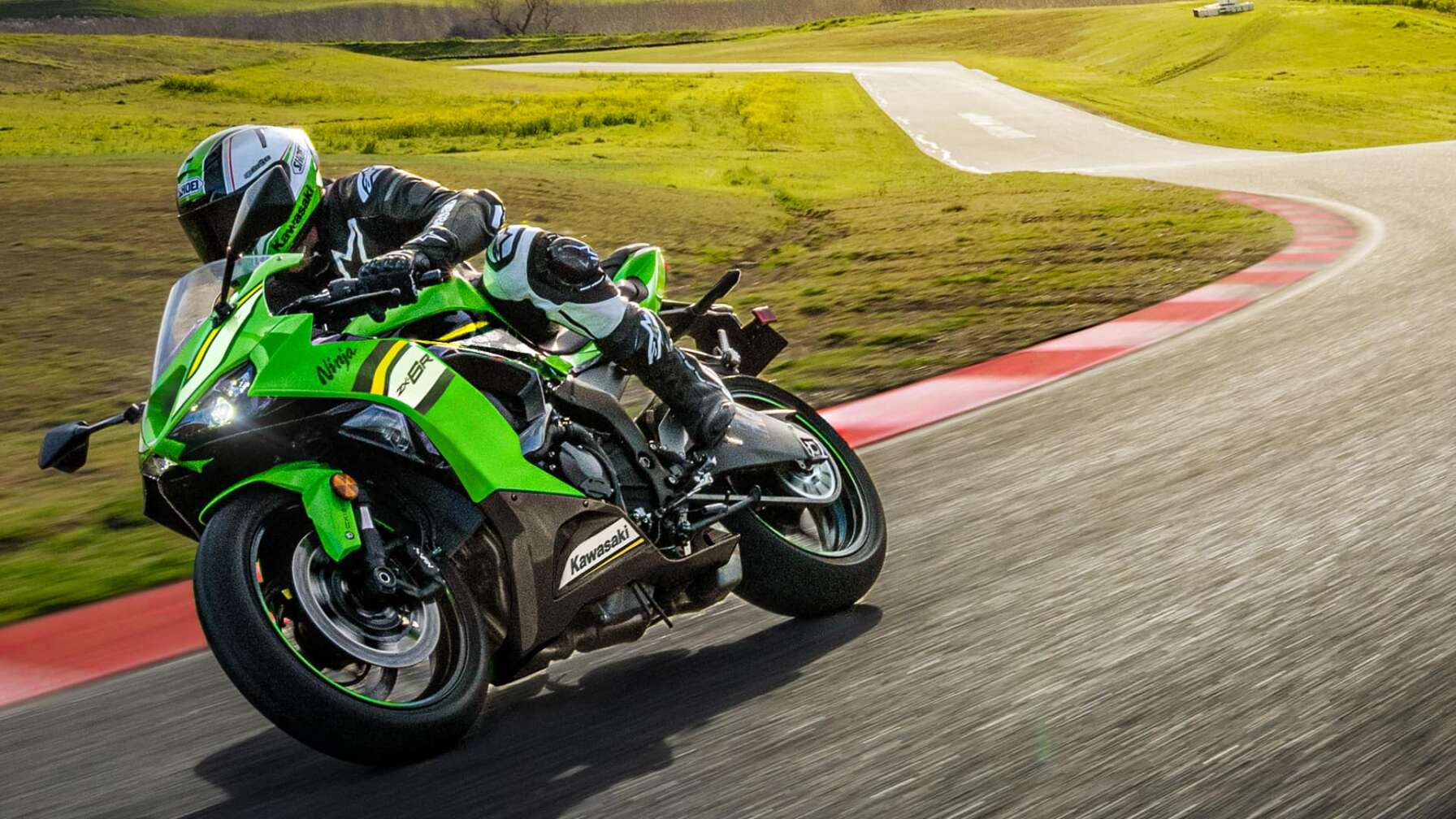 Eine Kawasaki Ninja ZX 6R fährt auf einer Rennstrecke, im Hintergrund Wiese