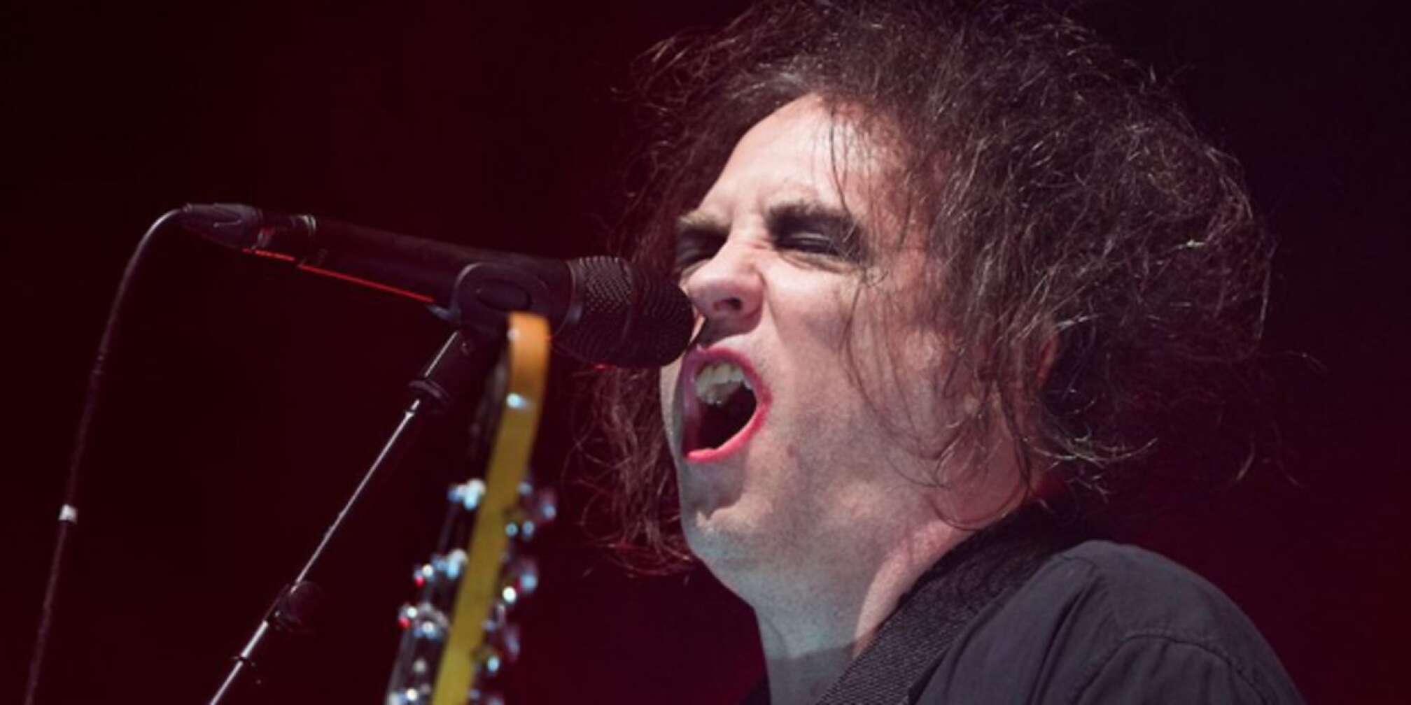 Robert Smith singt in ein Mikrofon mit geschlossenen Augen