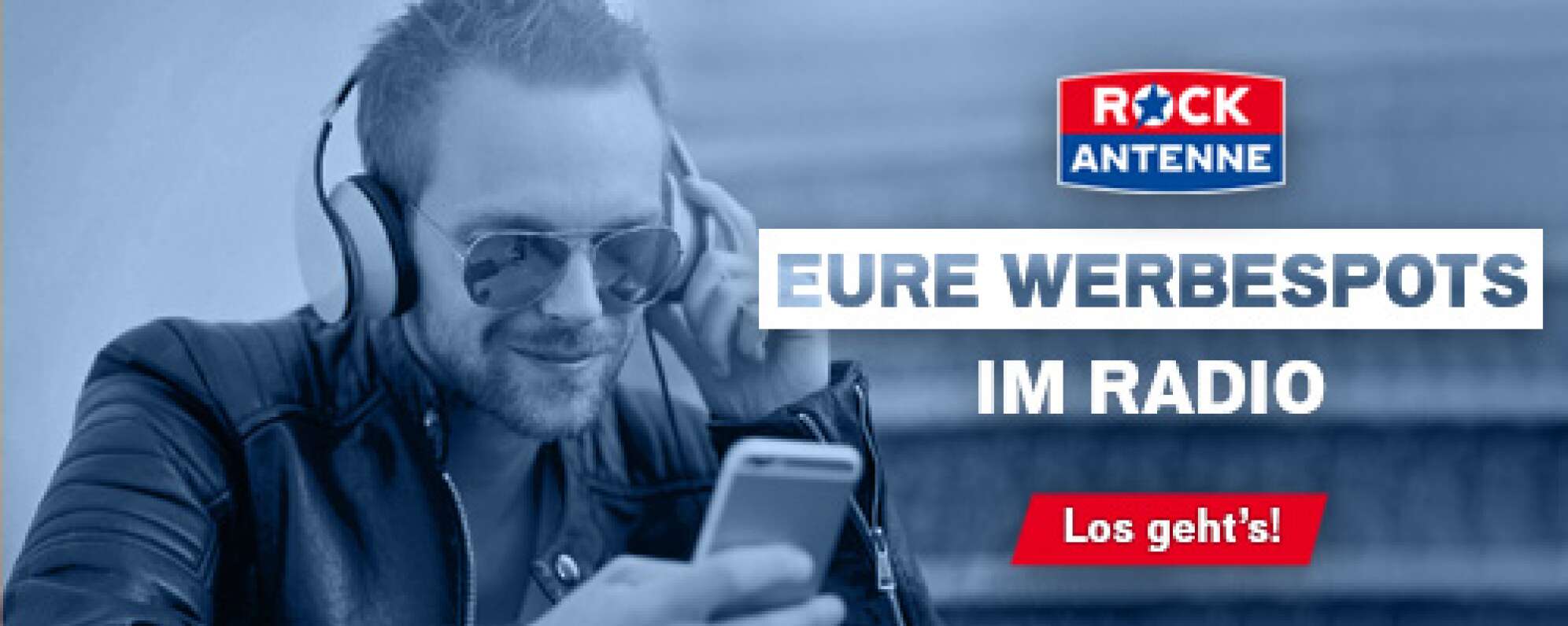 Bild eines Mannes mit Kopfhörern und Sonnenbrille, der auf ein Smartphone blickt und lächelt - dazu der  Text: Eure Werbespots im Radio - los gehts! und dazu das ROCK ANTENNE Logo