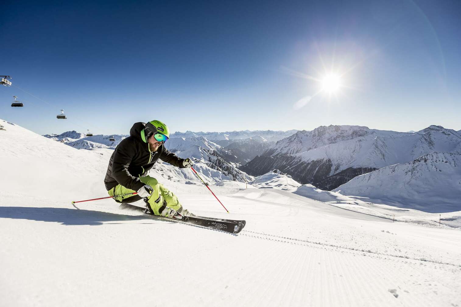 Foto eines Skifahrers vor dem herrlichen Panorama der schneebedeckten Berge in der Silvretta Arena in Samnaun/Ischgl