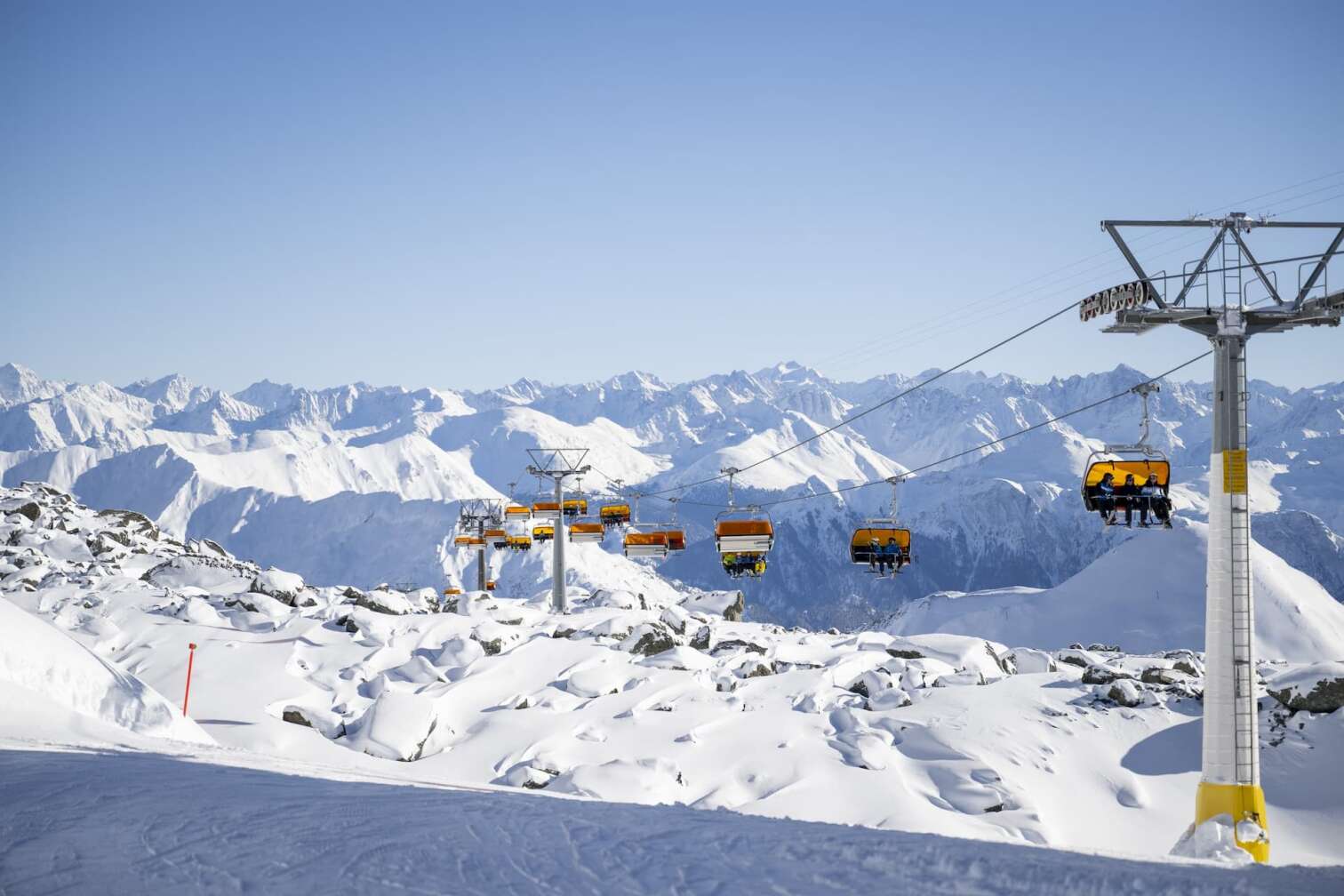 Foto eines Sessellifts vor dem herrlichen Panorama der schneebedeckten Berge in der Silvretta Arena in Samnaun/Ischgl