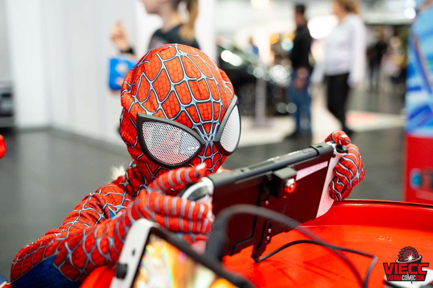 Ein Kind in Spiderman Kostüm spielt an einer Spielekonsole bei der Vienna Comic Con 2023